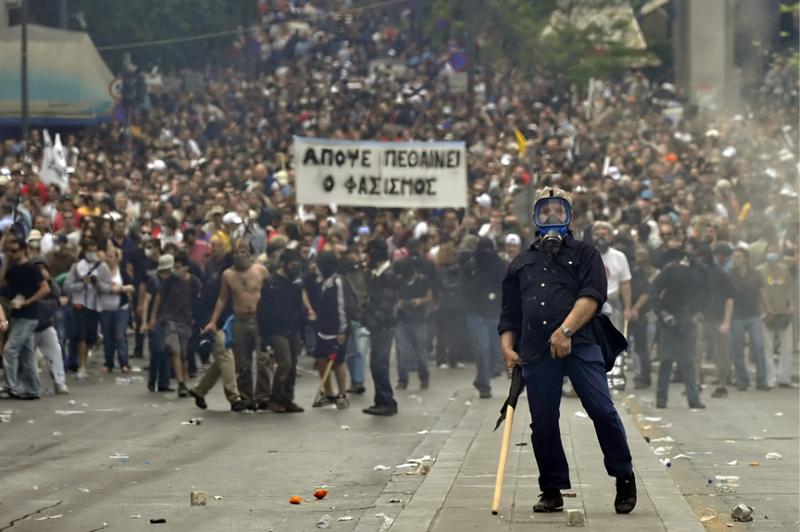 A protestor gestures to police near the Parliament building in the center of Athens.